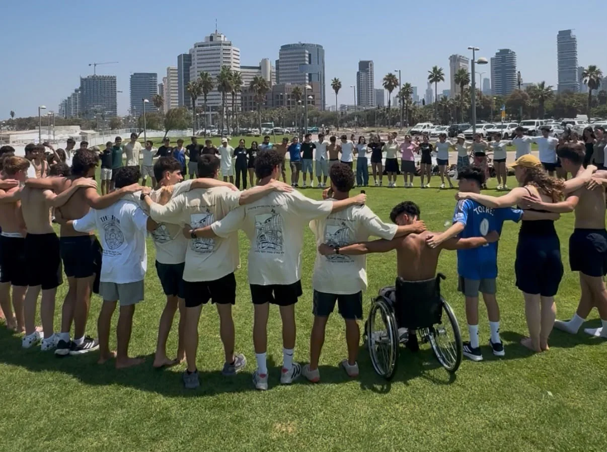 מעגל של עשרות בני נוער מחובקים במפגש של אושר בתל אביב